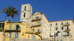 Gebäude, links eine Palme, vor blauem Himmel