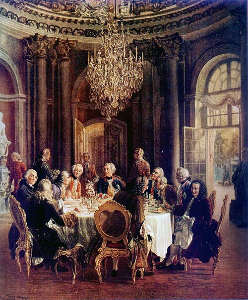 Die Tafelrunde Friedrichs II. in Sanssouci: Friedrich II. in der Mitte verfolgt das Gespräch zwischen Voltaire (zweiter Stuhl links des Königs) und Algarotti. Ölgemälde von Adolph von Menzel, 1850. (Copyright: Wikimedia Commons)