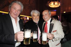 Drei Männer in schicker Kleidung und mit Bierkrügen in der Hand