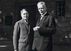 Schwarz-weißes Foto von zwei Männern im Anzug, auf einer Straße stehend