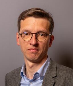 Portrait von Antoine Mordacq, kurze braune Haare, Brille, Hemd und Jacket