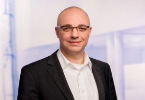 Portrait von Simon Franzmann, Brille, weißes Hemd und Jackett