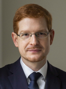 Portrait des Autors, rote Haare, Brille, kurzer Bart, Anzug mit Hemd und Krawatte