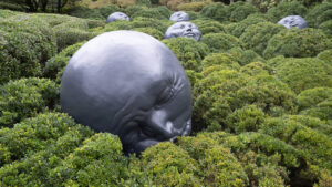 Graue Köpfe als Skulpturen in Büschen