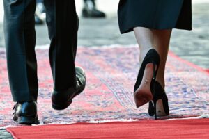 Ein paar Beine in Anzughosen und ein Paar Beine im Kleid auf einem roten Teppich