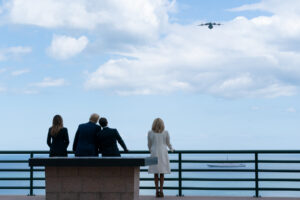 Melania Trump, Donald Trump, Emmanuel Macron und Brigitte Macron stehen mit dem Rücken zum Fotografen an einer Brüstung und schauen auf das Meer