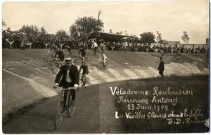Männer mit Anzügen und Hüten auf Fahrrädern in einem Velodrom