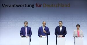 Gruppenbild während der Unterzeichnung des Koalitionsvertrags, vier Personen an Redepulten