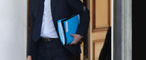 Mittlerer Teil des Körpers eines Menschen im Anzug mit Dokumentenmappe unter dem Arm