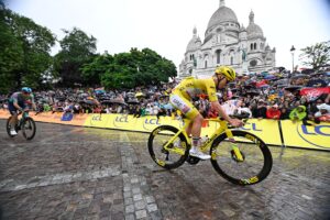 Fahrer im Gelben Trikot auf dem Fahrrad auf regennasser Straße vor der Basilika Sacré Coeur