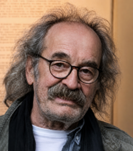 Mann mit runder Brille, langen Haaren und Schnurrbart