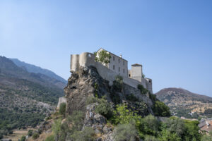 Festung auf einem Berg, in Hintergrund weitere Berge