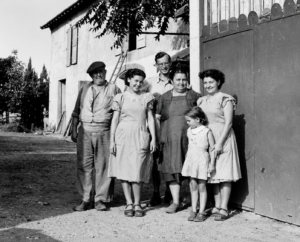 Drei Frauen, zwei Männer und ein Kind als Gruppenfoto vor einer Hauswand im Garten
