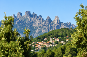 Blick auf ein kleines Dorf, im Hintergrund Berge